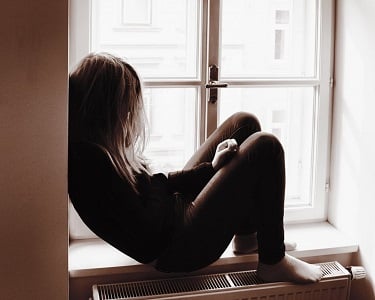 a girl feeling depressed and sitting in her window